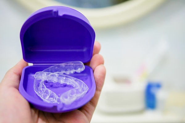 Person holding retainers in purple container